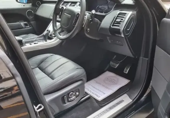 Immaculately detailed interior of a Range Rover, showcasing clean black leather seats and polished controls.