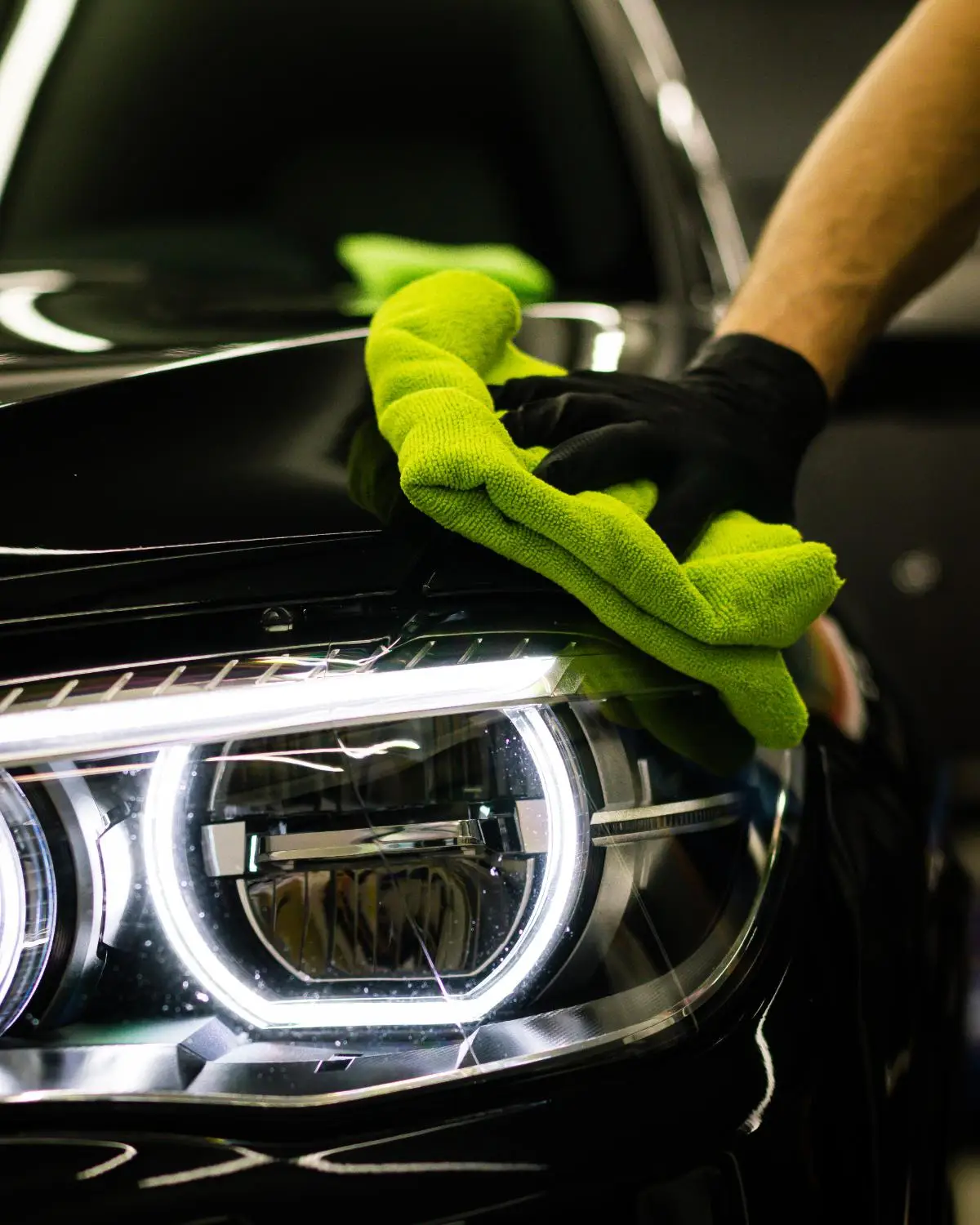 A detailer machine-polishing a car headlight back to clarity
