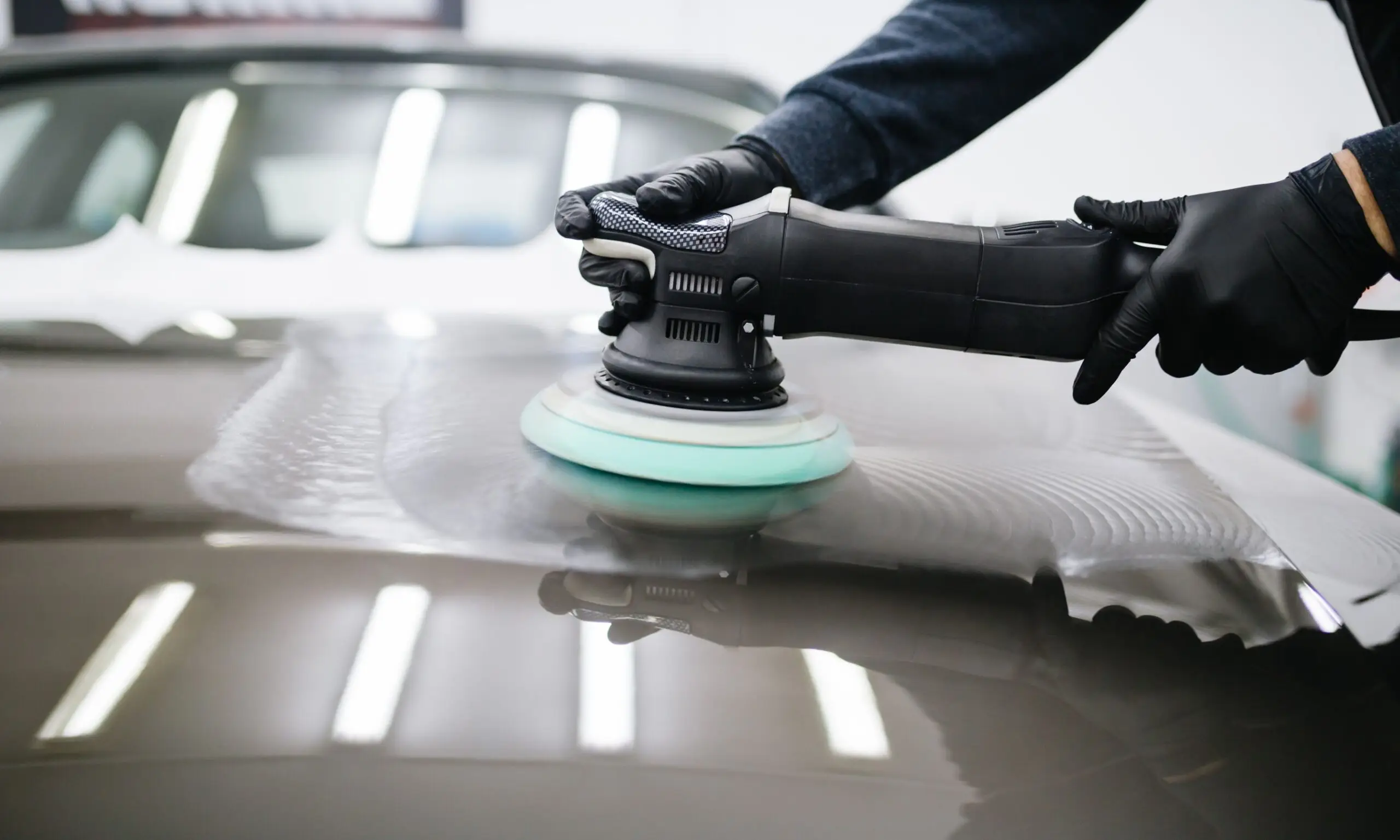 Close-up of a car bonnet undergoing machine polishing during a paint correction process.